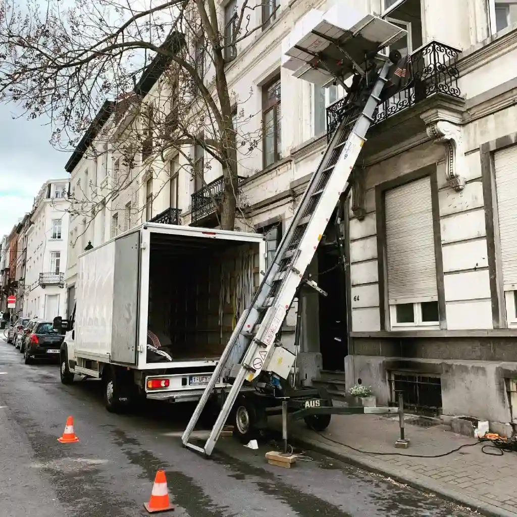Operarios de Mudena utilizando una plataforma elevadora en León para subir muebles por la fachada de un edificio